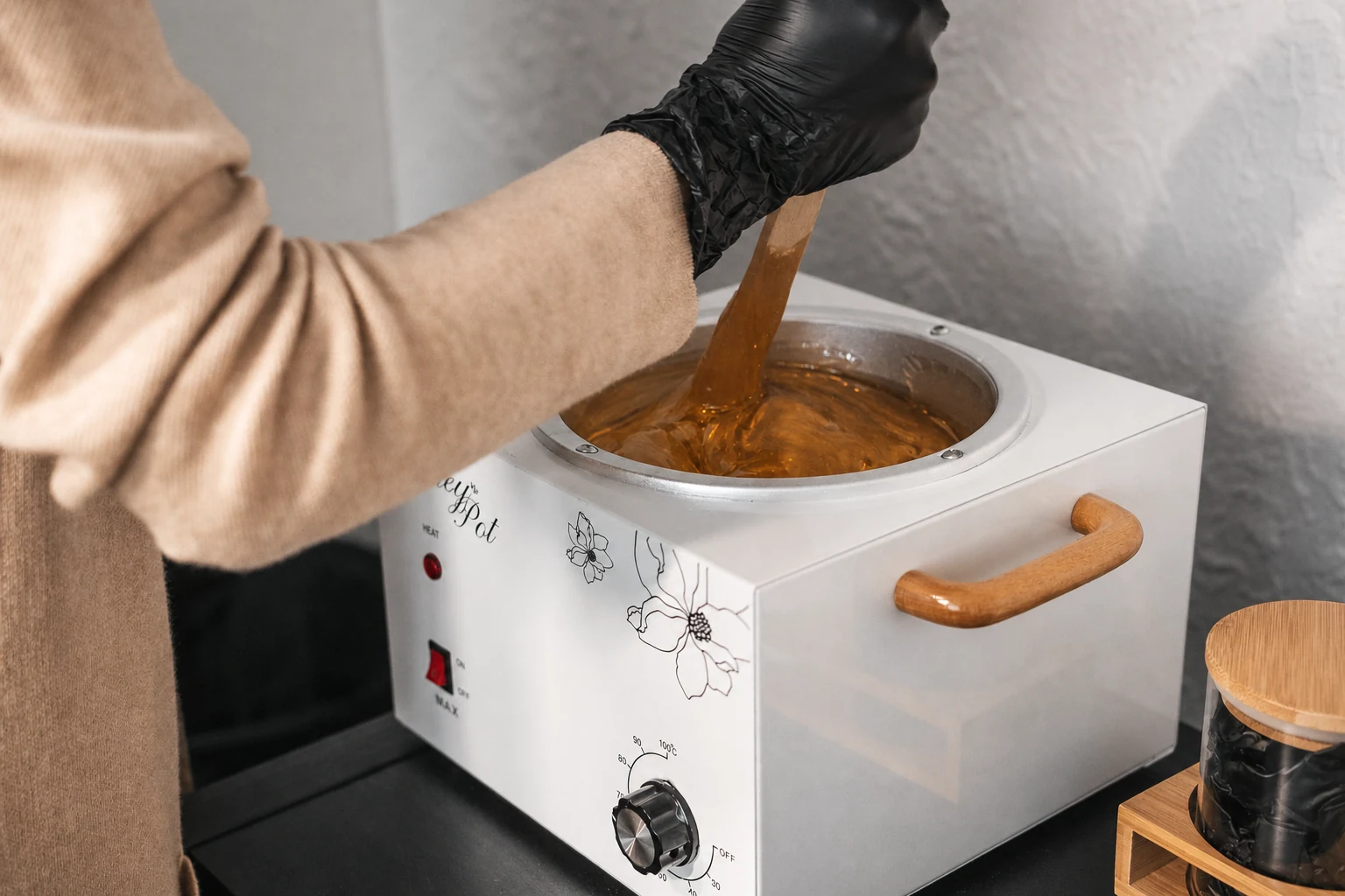 Professional warm amber wax being prepared with a disposable wooden spatula